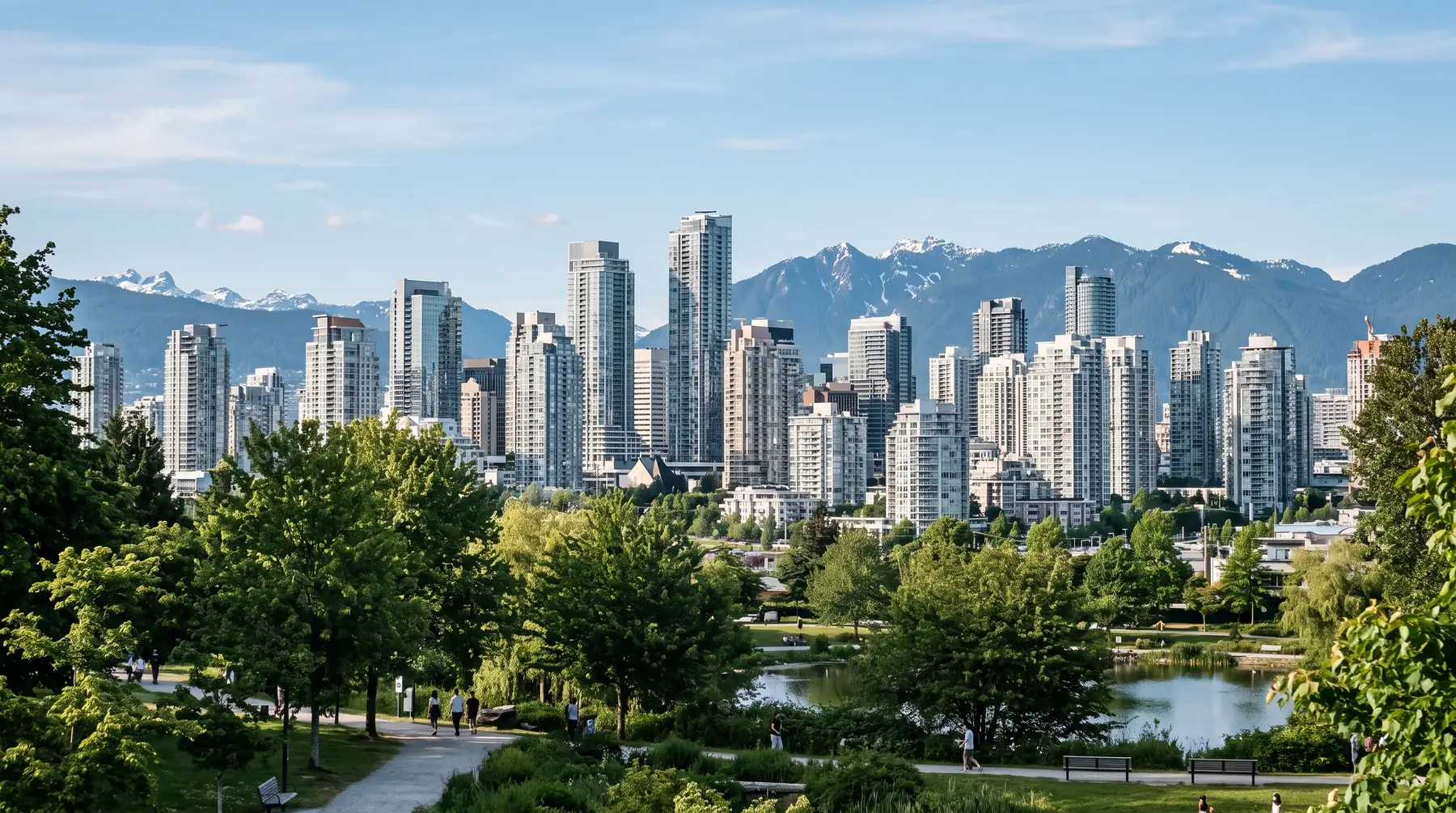 Lower Mainland skyline of residential and office towers with trees in the foreground and mountains behind